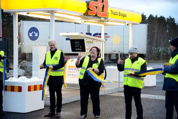 Tre personer i gula varselvästar klipper ett invigningsband framför en St1 Truck-station.
