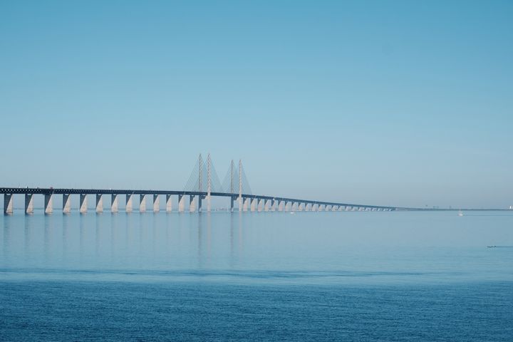 Bild av Øresundsbron som sträcker sig över ett lugnt hav under en klar himmel.