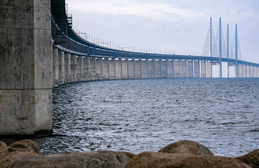 En bild av Øresundsbron som sträcker sig över vattnet under en molnig himmel.