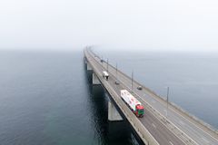 Flygbild av en lastbil som kör över Öresundsbron i disigt väder, med bron som försvinner i dimman över havet.