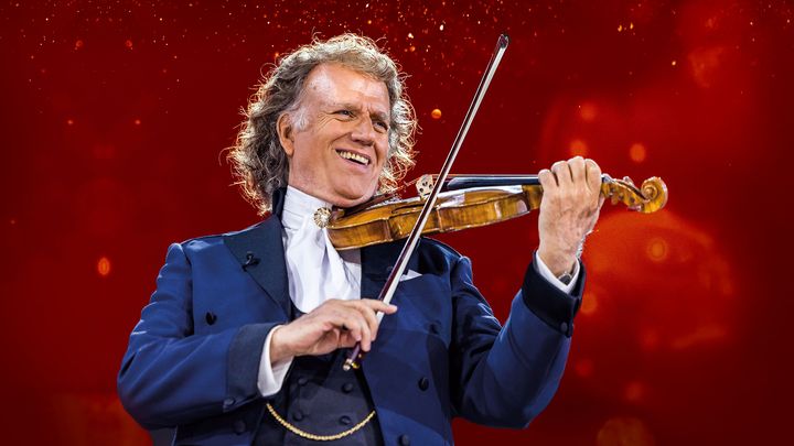 André Rieu spelar på sin violin mot röd bakgrund.