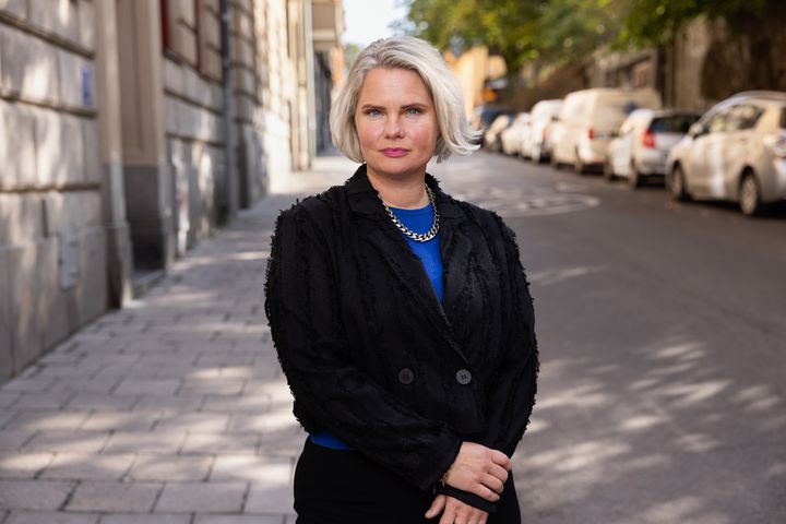 Ida Wanngård, med ljust hår, blå tröja och svart kofta, i gatumiljö.