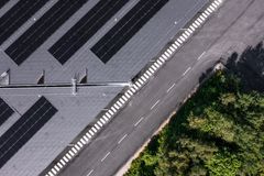 Flygbild av Växjö stadsbussdepå med solpaneler på taket bredvid en väg med vita markeringar och grönska.