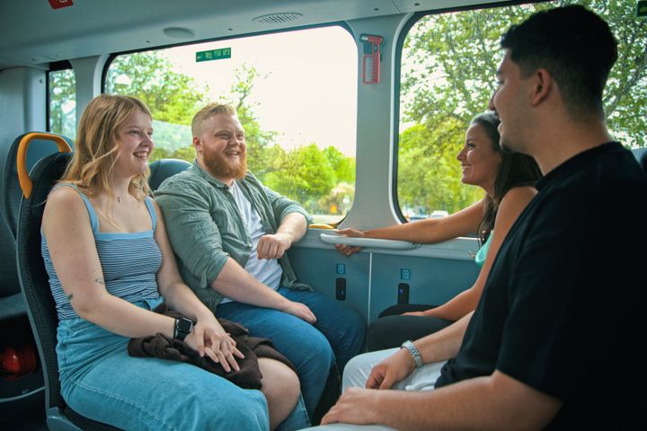 En grupp människor som ler och pratar på en buss.