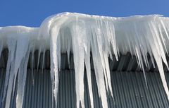 Snö och istappar hänger från ett tak.