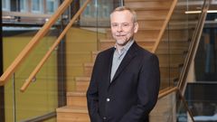 Man i mörk kavaj ståendes framför en trappa.