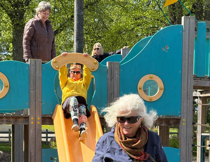 Äldre kvinnor åker rutschkana utomhus i lekpark.