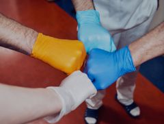 Fyra olikfärgade handskbeklädda nävar möts i en knut.