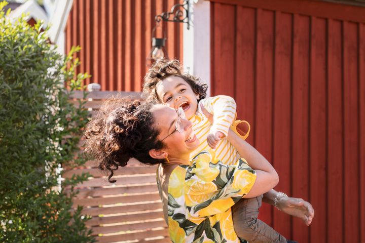 Foto med glad kvinna som lyfter ett barn