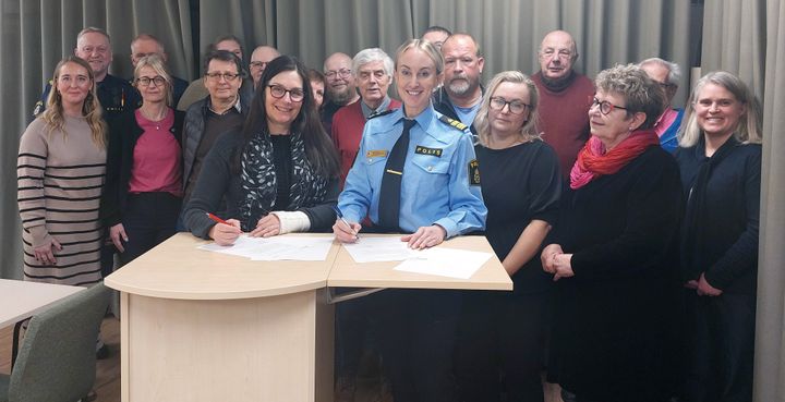 Kommunstyrelsens ordförande Catarina Pettersson och lokalpolisområdeschef Maria Bäck undertecknar medborgarlöftet omgivna av kommunstyrelsen.