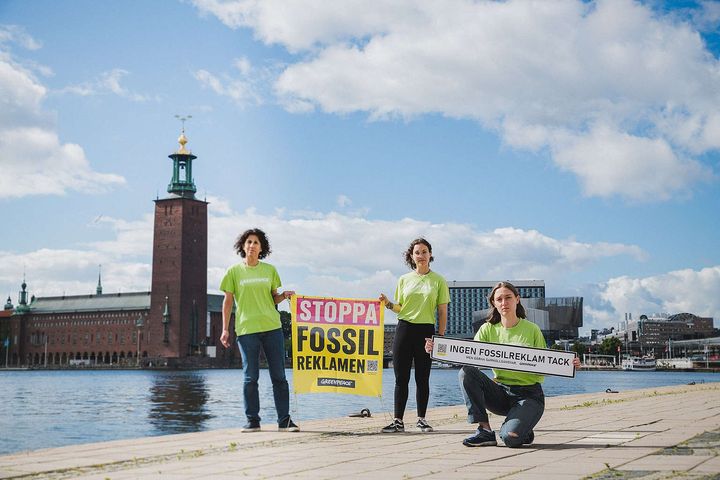 Greenpeaceaktivister med banderoller uppmanar till ett förbud mot fossilreklam i Stockholm. ©Jana Eriksson/Greenpeace