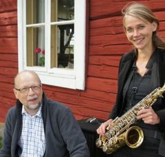 Bild på man som sitter och kvinna med saxofon som står