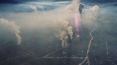 Flygbild över Zenica med fabriker som släpper ut rök, dimma täcker staden.