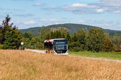 En elbuss på en landsväg intill ett fält.