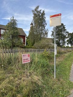 En busshållplats och skylt i gräset vid en kyrka
