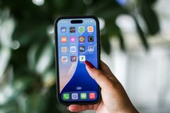 En hand som håller i en mobiltelefon med appar på skärmen