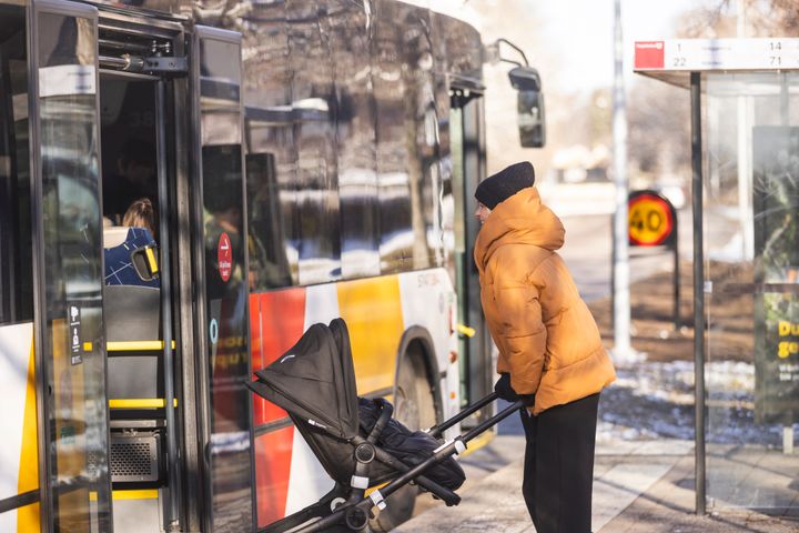 kvinna med barnvagn vid en buss