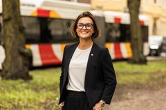 En kvinna i mörk kavaj och vit tröja, som tittar in i kameran och ler.