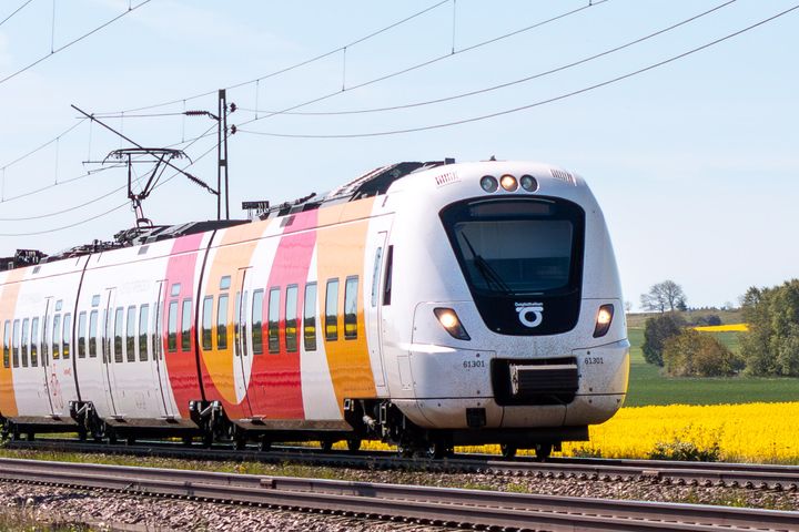 Ett tåg som åker utmed gula rapsfält