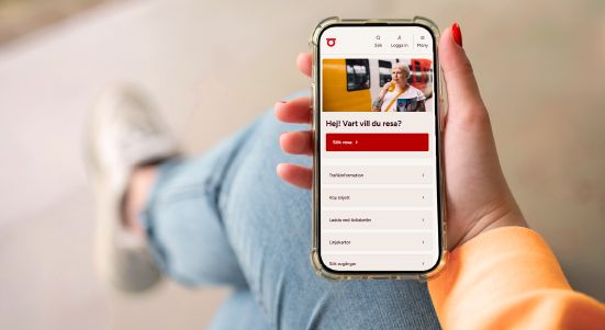 En person håller i en mobil med Östgötatrafikens nya webb.