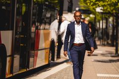 En man i kavaj som går vid en buss på en hållplats