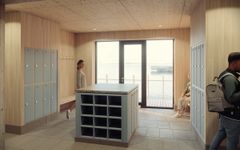 Bild av ett modernt rum med träväggar, ljusblåa skåp och en central förvaringsö. Fönster i bakgrunden släpper in naturligt ljus. Flera personer är i rummet.