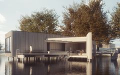 Ett modernt kallbadhus vid vattnet, omgivet av träd.