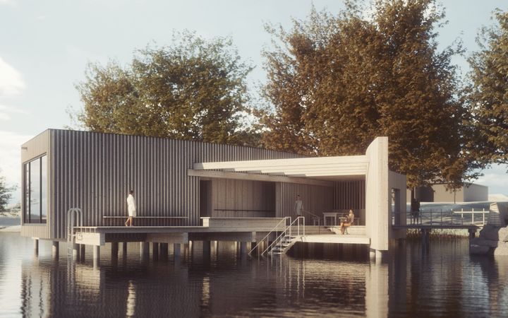 Ett modernt kallbadhus vid vattnet, omgivet av träd.