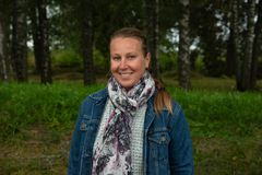 Porträttbild på Anna-Eva Olsson, som står framför träd ute i naturen.