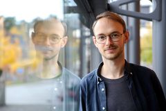 Porträtt på sam de Boise. Hans ansikte speglarsig i ett fönster bredvid