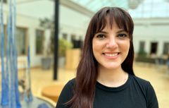 En leende Inês Trindade mot en luftig bakgrund inomhus på Örebro universitet