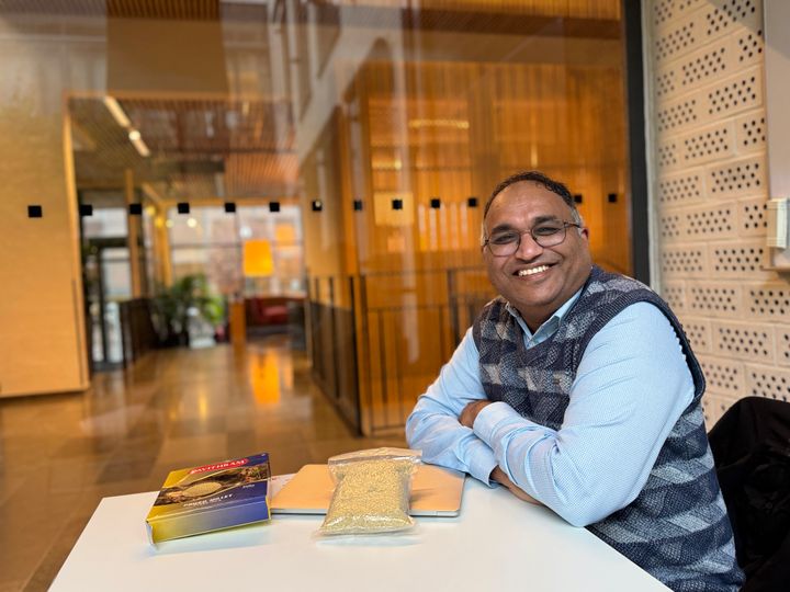 Man vid bord som ler och har pakter framför sig