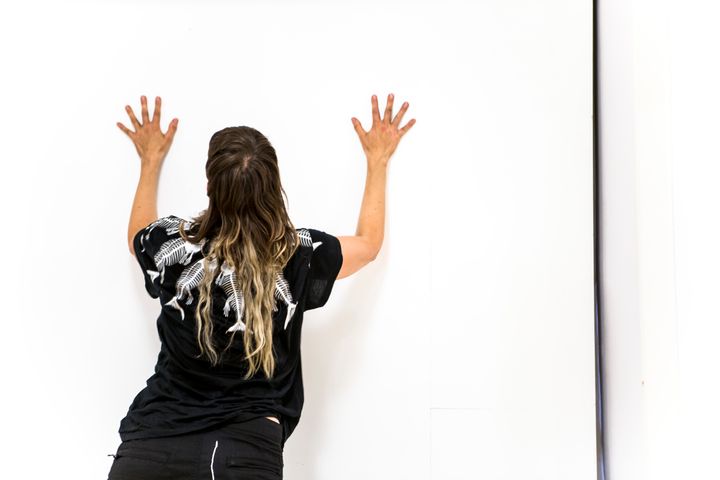 En dansare står med händerna mot väggen.