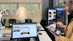 På surfplattan ritas hur kabeln ska dras. Robotarmen i bakgrunden flyttar sedan självständigt kabeln till rätt plats.