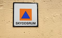 En plåtskylt på en gul husfasad med texten: Skyddsrum