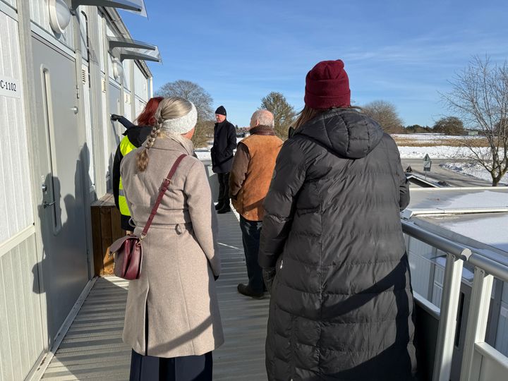 En grupp människor under ett studiebesök vid en byggarbetsplats i Visby.