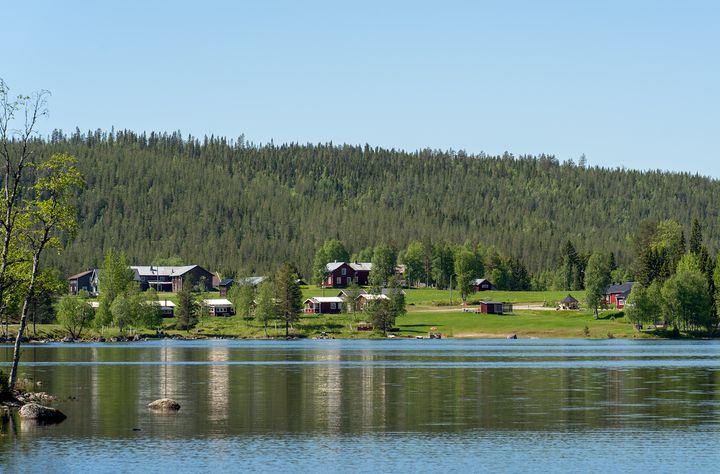 Norrländsk sjö med närliggande by i somrig miljö.