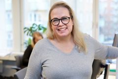 En person som ler och står i ett kontor.