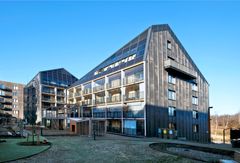 Modernt flerfamiljshus i Norra Djurgårdsstaden med solpaneler på taket.