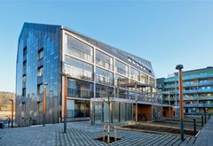 Bild på Stockholmshems plusenergihus i Norra Djurgårdsstaden, med modern arkitektur och solpaneler på taket.