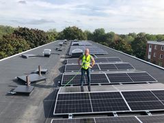 En person står på ett tak med solpaneler i Bagarmossen, Stockholm.