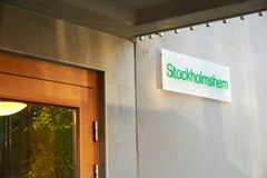 Bild på en skylt med texten "Stockholmshem" vid en husfasad.
