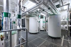 Bild på undercentralen i Stockholmshems plusenergihus i Norra Djurgårdsstaden, med rör och stora cylindrar.