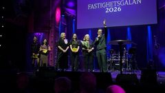 En grupp personer står på scenen vid Fastighetsgalan 2026, med en person som håller upp en mikrofon.