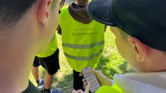Ungdomar i varselvästar tittar på en mobiltelefon