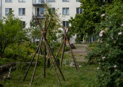 Gård vid flerbostadshus med naturlekplats och grönskande omgivning.