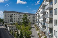 Flervåningshus med grönskande gård, växtbäddar och gångväg.