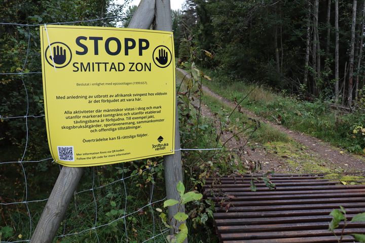 Soppskyllt med information om smittzon vid ett skogsområde.