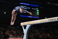 Kvinna utför gymnastik övning på bom under en tävling.