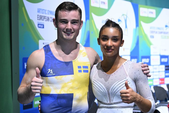 Två gymnaster i tävlingsdräkter står bredvid varandra och ger tummen upp.